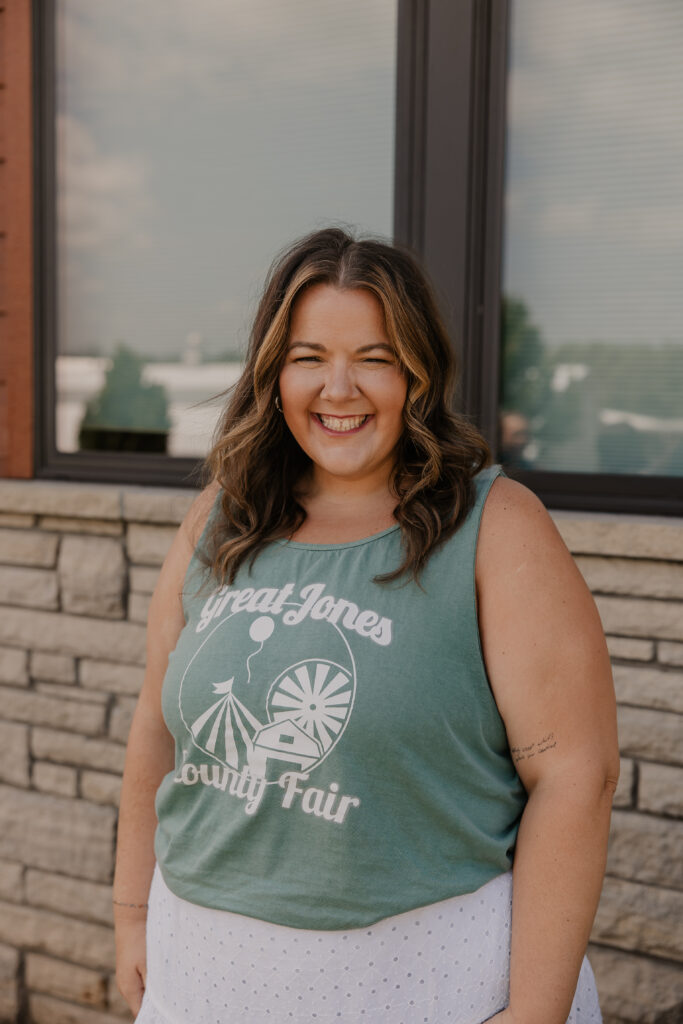 Abby Jaeger stands in front of the fair office in a Great Jones County Fair shirt