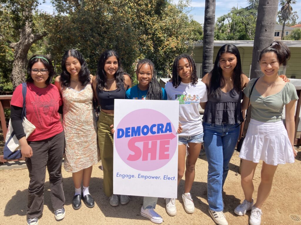 f mixed ethnicities stand with a DemocraShe sign